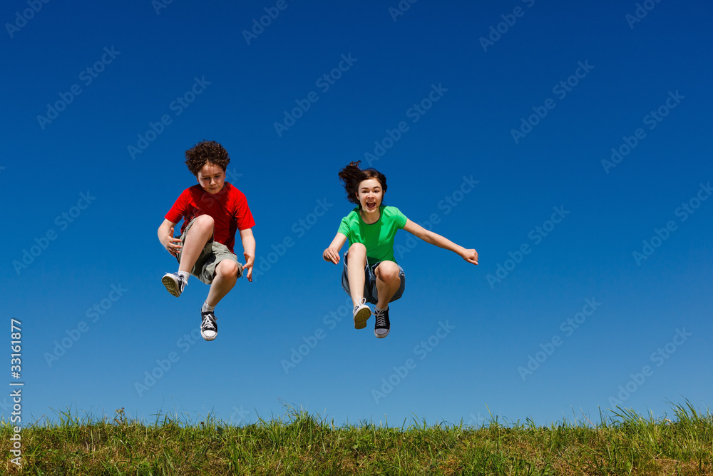 Girl and boy jumping, running against blue sky Girl and boy jumping, running against blue sky