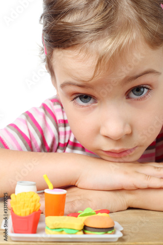 little girl, toy french fries, cola and hamburger on table