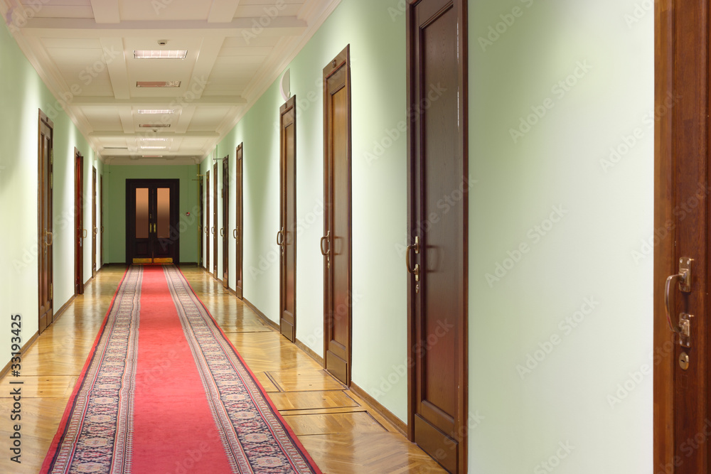 long hallway with brown wood doors, door at end of corridor Stock Photo Adobe Stock