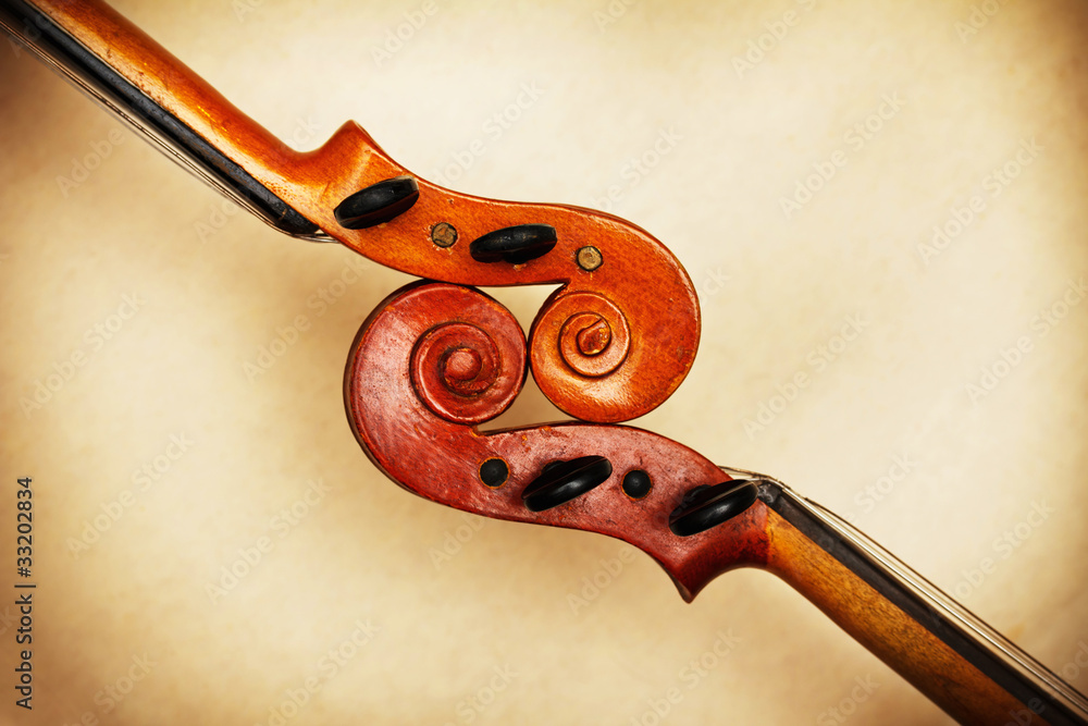 Naklejka premium two old violin scrolls detail in ambient light