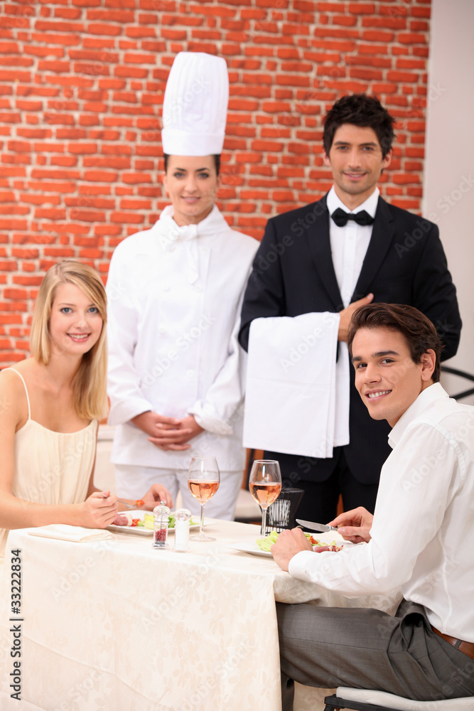 A couple being served by a waiter and a chef in a restaurant A couple being served by a waiter and a chef in a restaurant
