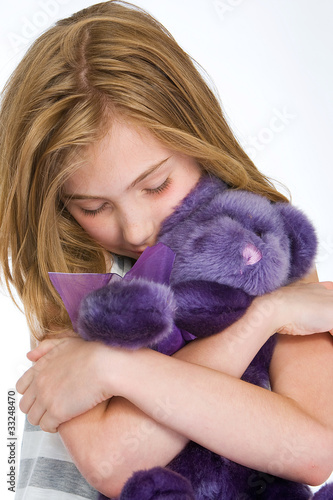 kid hugging a purple teddy bear