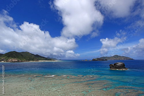 慶良間島の澄んだ珊瑚礁の海と白い雲