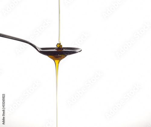 Honey pouring over a spoon on a white background