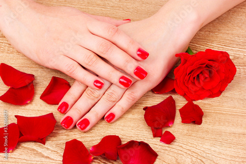beautiful red manicure and  flower on a wooden background