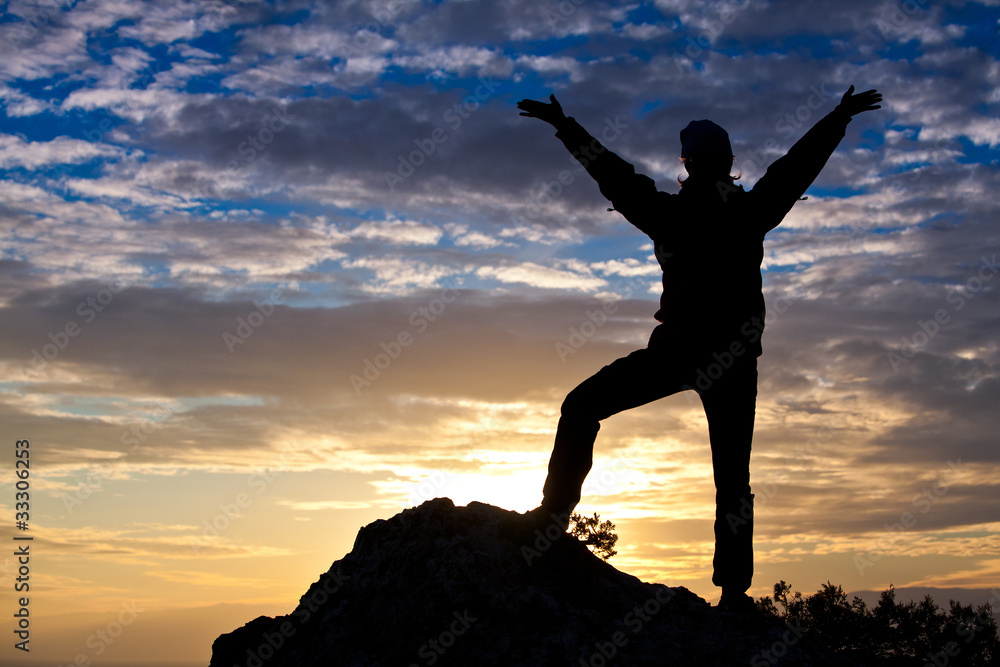 Silhouette of a woman on top of the mountain at the sea while su Silhouette of a woman on top of the mountain at the sea while su
