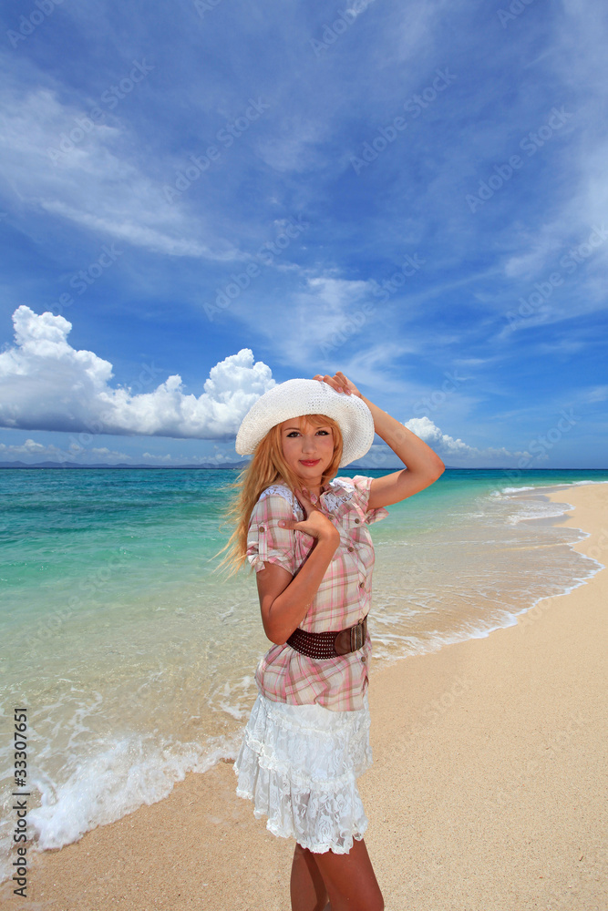 真っ白い砂浜の上に立つ笑顔の女性