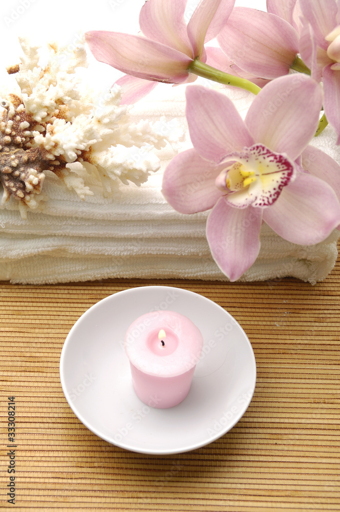 Pink orchid and seashell on towel with towel on mat