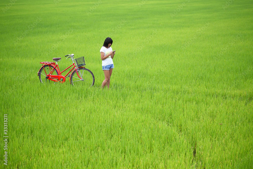 Beautiful girl plaing a phone with bike in paddy field Beautiful girl plaing a phone with bike in paddy field