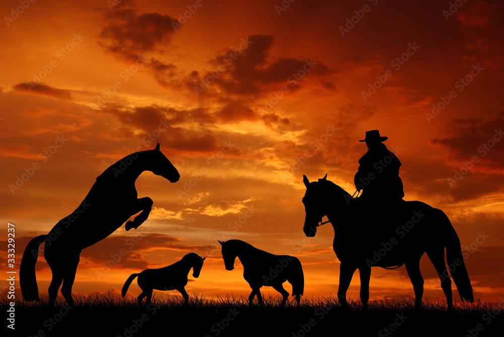 Silhouette cowboy with horses in the sunset