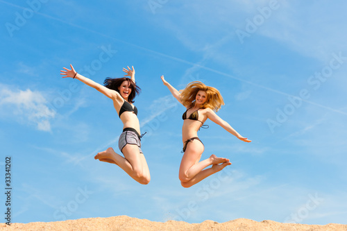 Zwei glückliche Frauen springen hoch mit Spaß