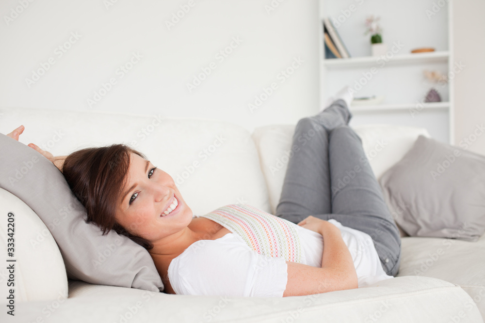 Good looking brunette woman posing while lying on a sofa Good looking brunette woman posing while lying on a sofa