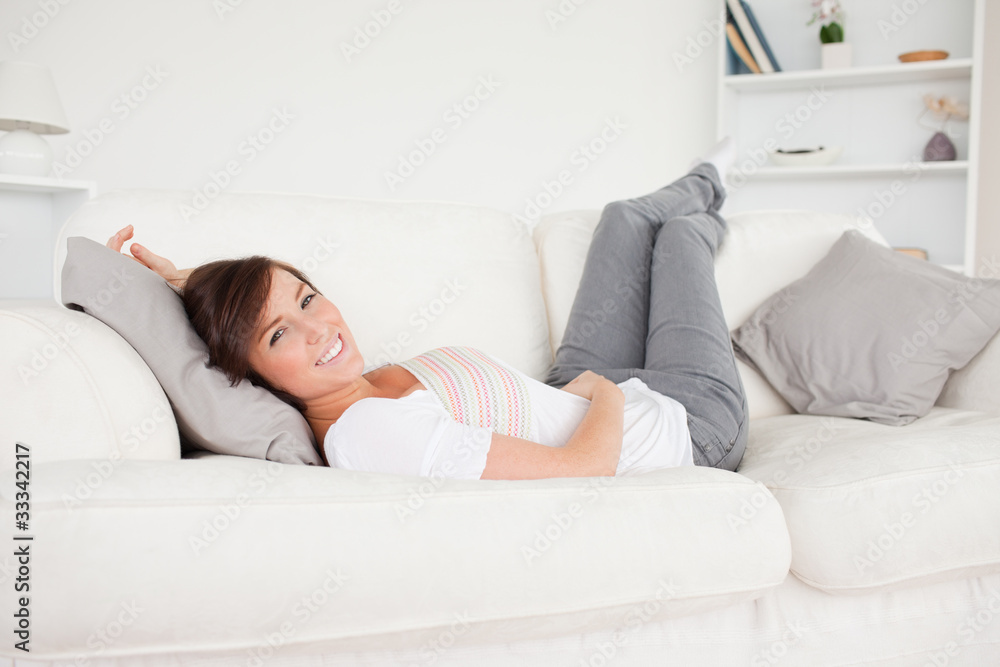 Charming brunette woman posing while lying on a sofa Charming brunette woman posing while lying on a sofa