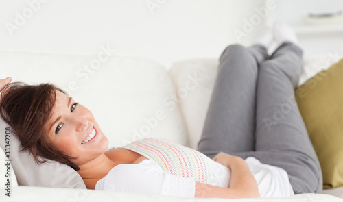 Attractive brunette woman posing while lying on a sofa