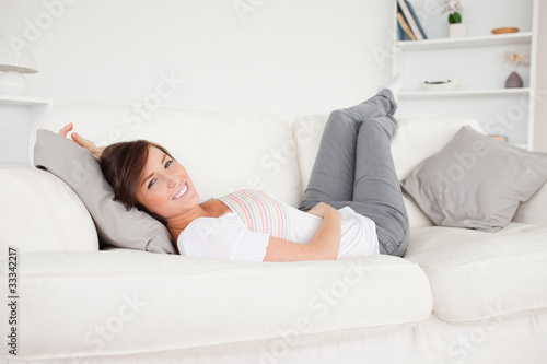 Charming brunette woman posing while lying on a sofa