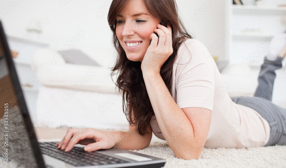 Pretty brunette woman on the phone while relaxing with her lapto Pretty brunette woman on the phone while relaxing with her lapto
