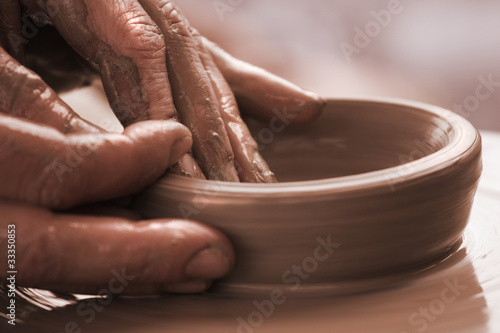 human hands moulding with the clay on a potter`s wheel close up. photo