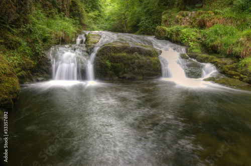 Fototapeta Naklejka Na Ścianę i Meble -  Stunning waterfall flowing over rocks through lush green forest