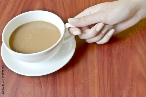 female hand with manicure holdig a cup of coffee