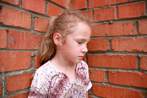 Bild auf Leinwand sad child in front of a brick wall
