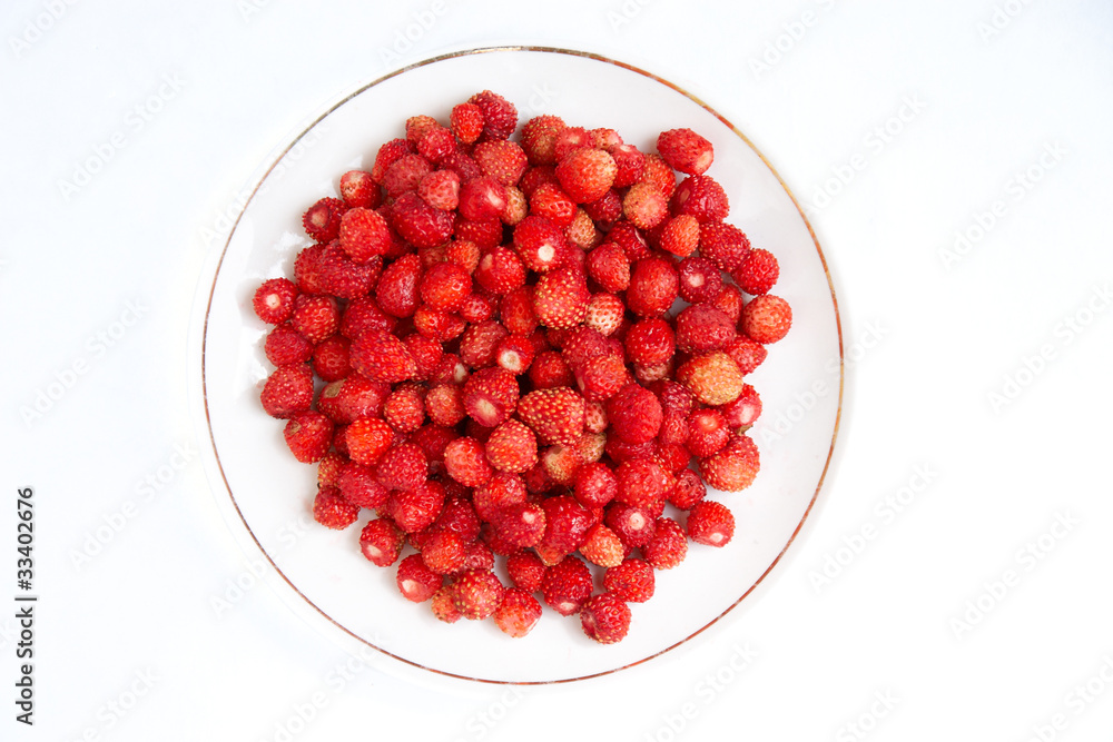 Top view of plate full of wild strawberries isolated on white Top view of plate full of wild strawberries isolated on white