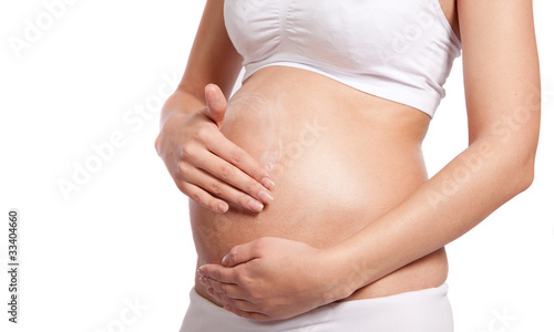 young pregnant woman rubs cream into her belly © narcis1