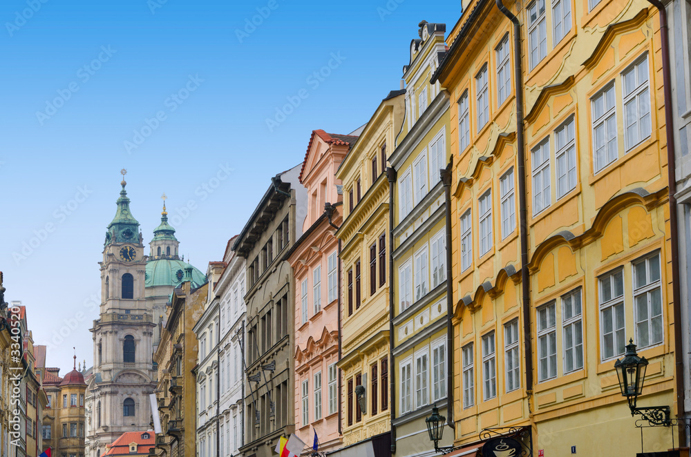 Prague street with colorful houses and church with clock tower