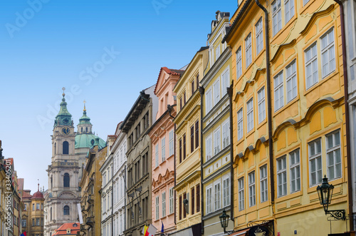 Prague street with colorful houses and church with clock tower