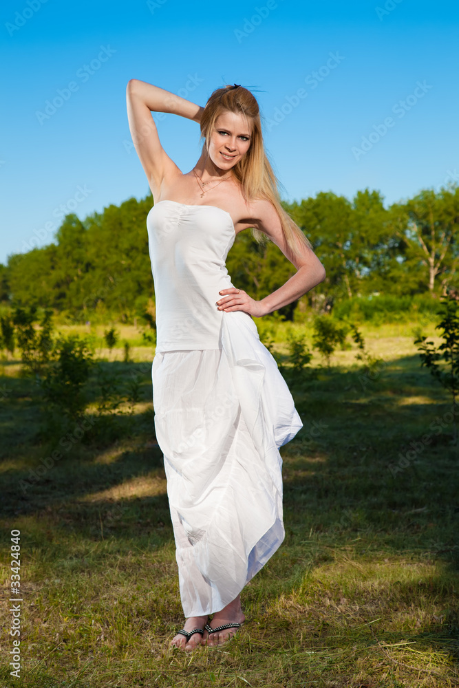 Young blond woman in white dress in the park Young blond woman in white dress in the park