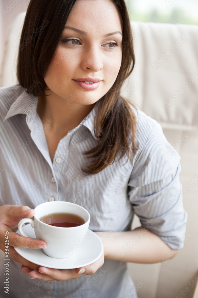 Young woman at home sipping tea from a cup