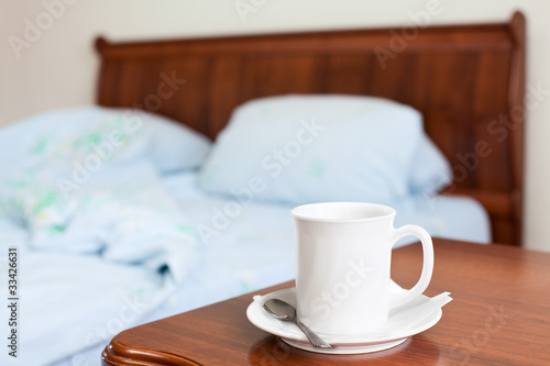 White cup on a bedside nightstand in the bedroom