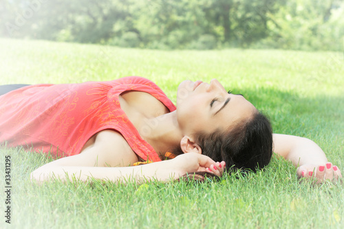 Young woman relaxing on green grass at the park
