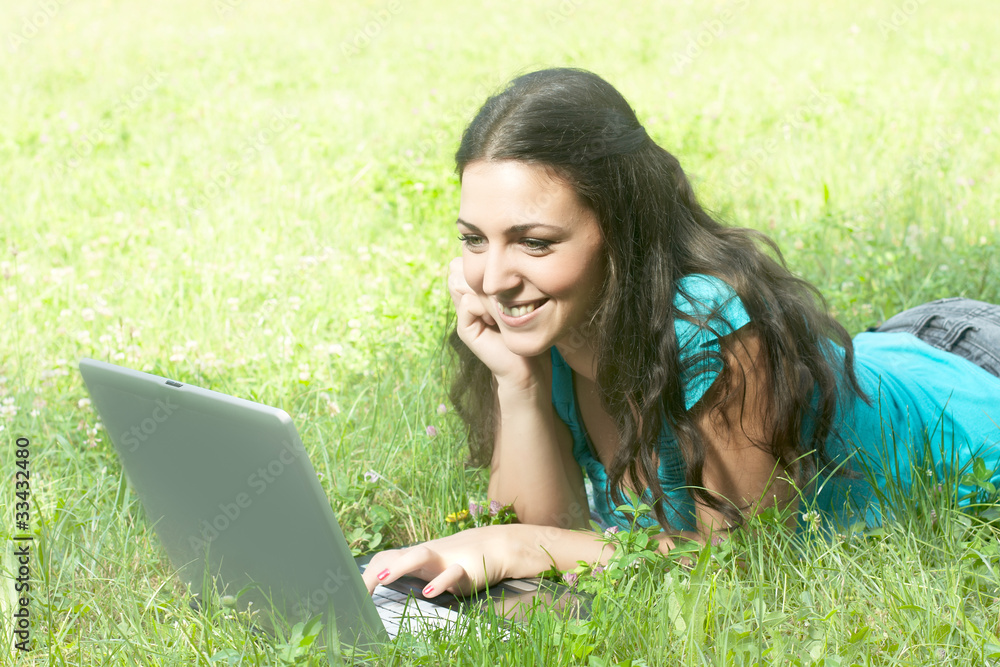Young woman with laptop lying on grass Young woman with laptop lying on grass