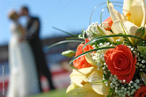 Wedding bouquet against a newly married couple (close-up)