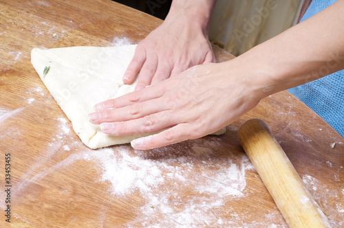 hands in flour closeup kneading dough on table