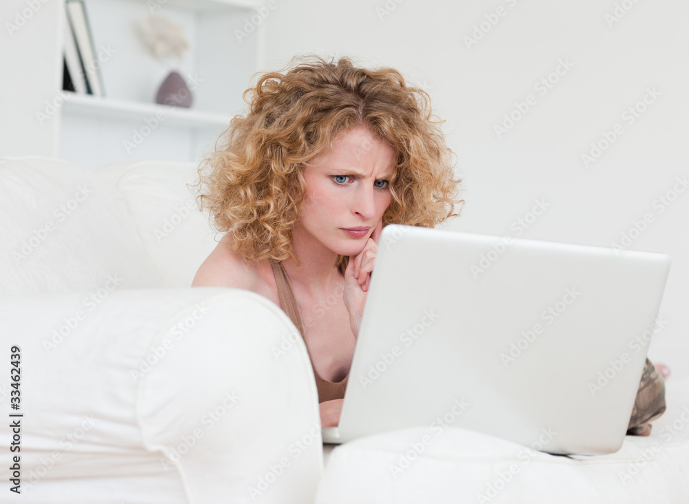 Upset blonde female relaxing with her laptop while sitting on a Upset blonde female relaxing with her laptop while sitting on a