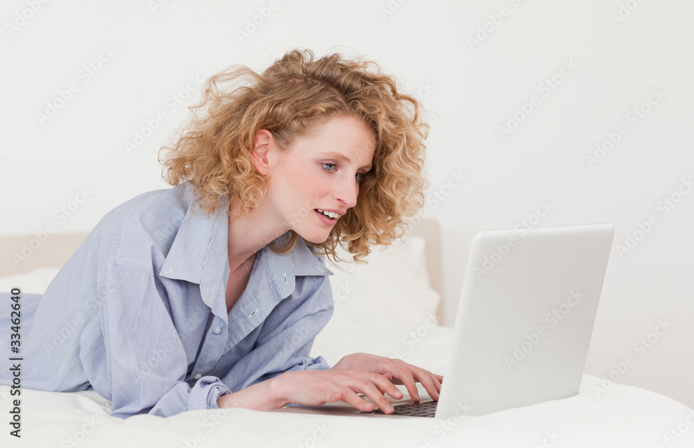 Gorgeous blonde woman relaxing with her laptop while lying on he Gorgeous blonde woman relaxing with her laptop while lying on he