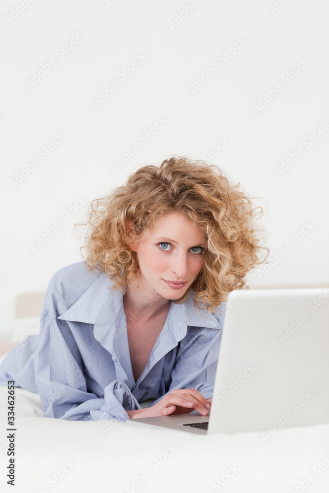 Good looking blonde female relaxing with her laptop while lying Good looking blonde female relaxing with her laptop while lying