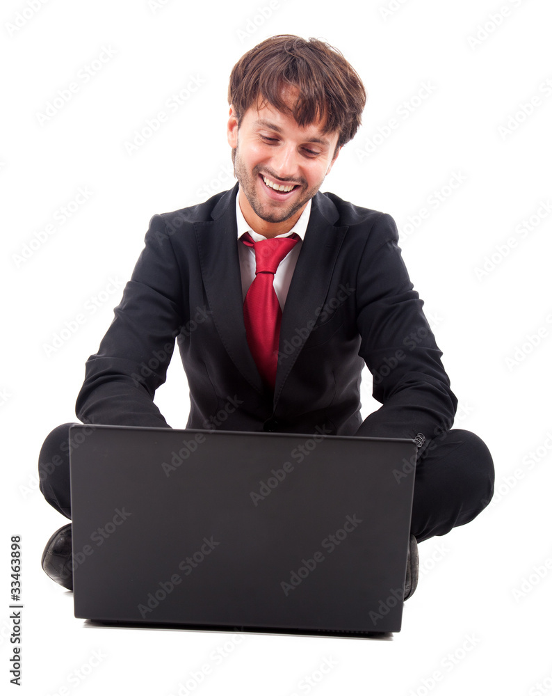 Smiling businessman sitting on the floor using his laptop Smiling businessman sitting on the floor using his laptop