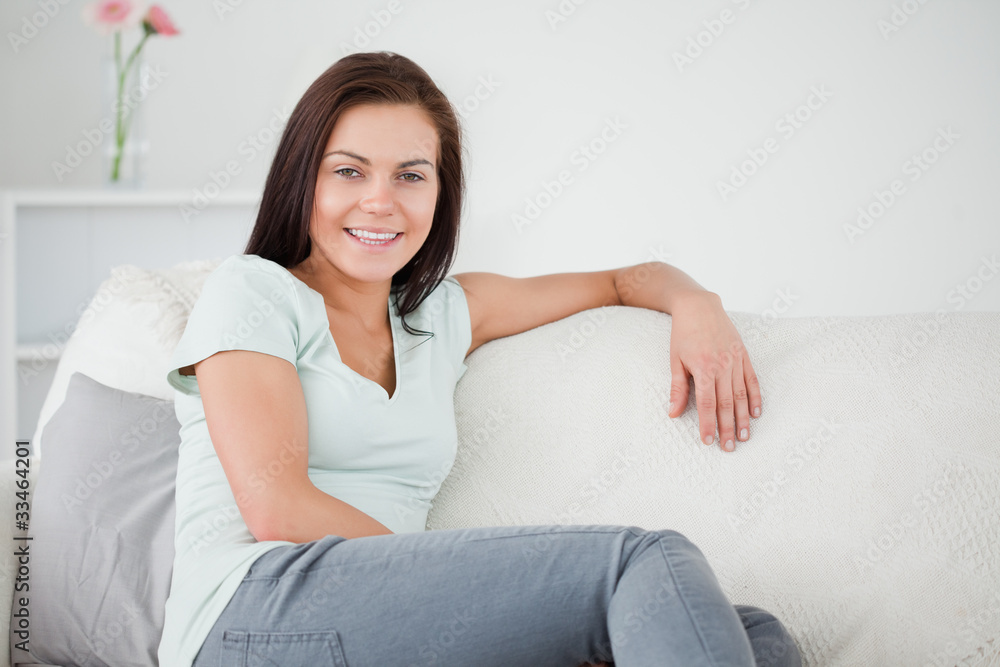 Close up of a smiling brunette onn a sofa looking at the camera Close up of a smiling brunette onn a sofa looking at the camera