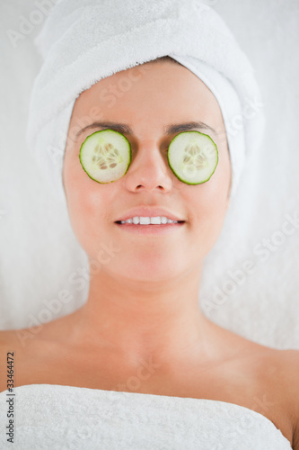 Smiling woman with cucumber slices on the face