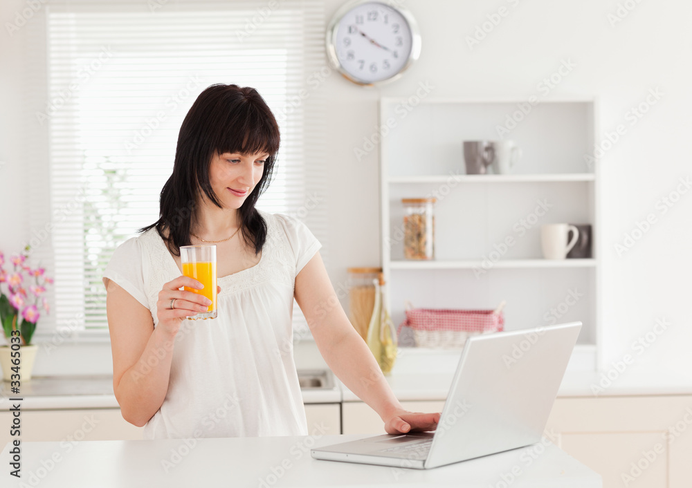 Beautiful brunette woman holding a glass of orange juice while r Beautiful brunette woman holding a glass of orange juice while r
