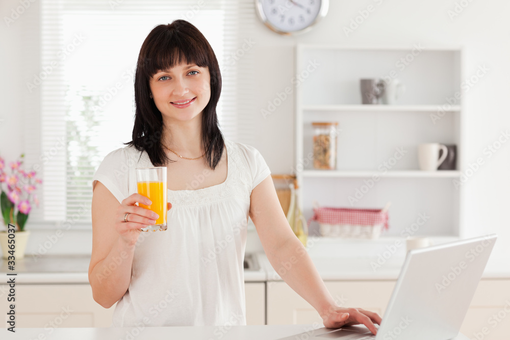 Gorgeous brunette woman holding a glass of orange juice while re Gorgeous brunette woman holding a glass of orange juice while re