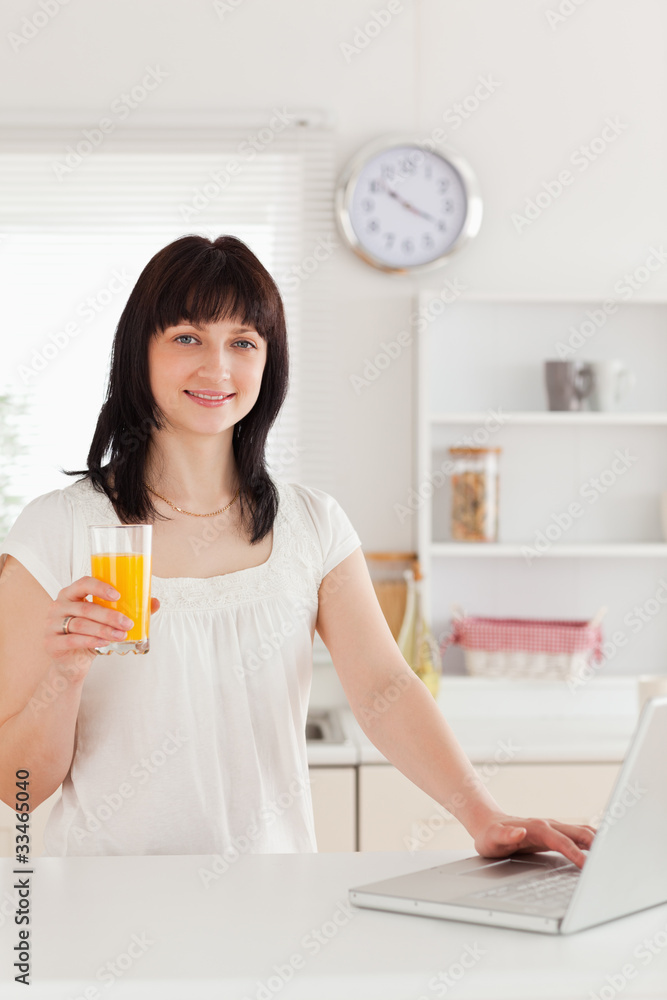 Cute brunette woman holding a glass of orange juice while relaxi Cute brunette woman holding a glass of orange juice while relaxi