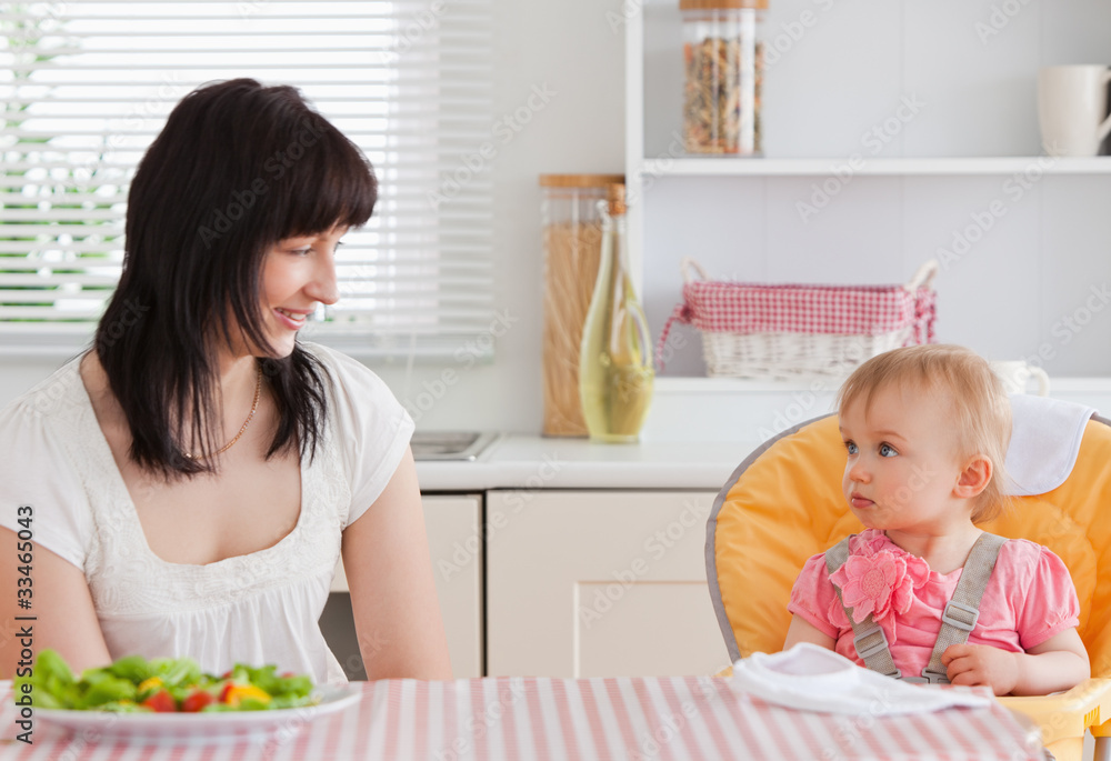 Gorgeous brunette woman having a meal with her baby while sittin Gorgeous brunette woman having a meal with her baby while sittin