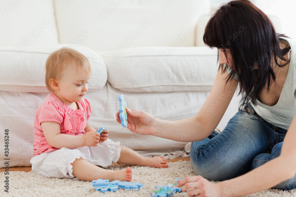 Beautiful woman and her baby playing with puzzle pieces while si Beautiful woman and her baby playing with puzzle pieces while si