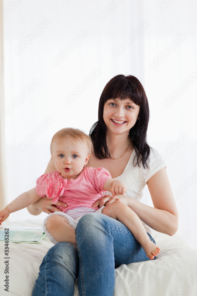 Attractive brunette woman holding her baby on her knees while si Attractive brunette woman holding her baby on her knees while si