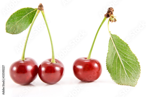 Three cherry fruits with leaves.