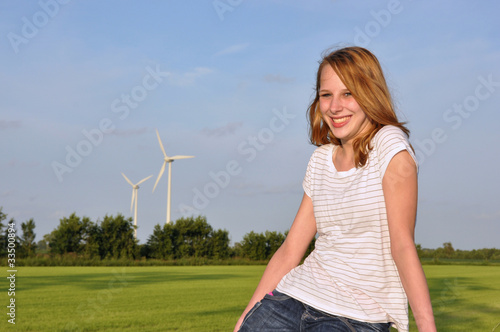 Girl posing in agricultural scene with wind turbine