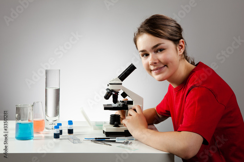 Girl examining preparation under the microscope